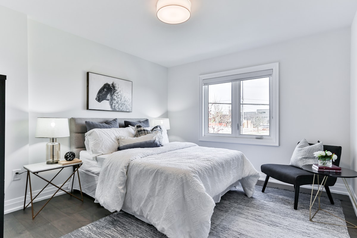 Furnished bedroom with a made-up double bed, bedside tables and an armchair